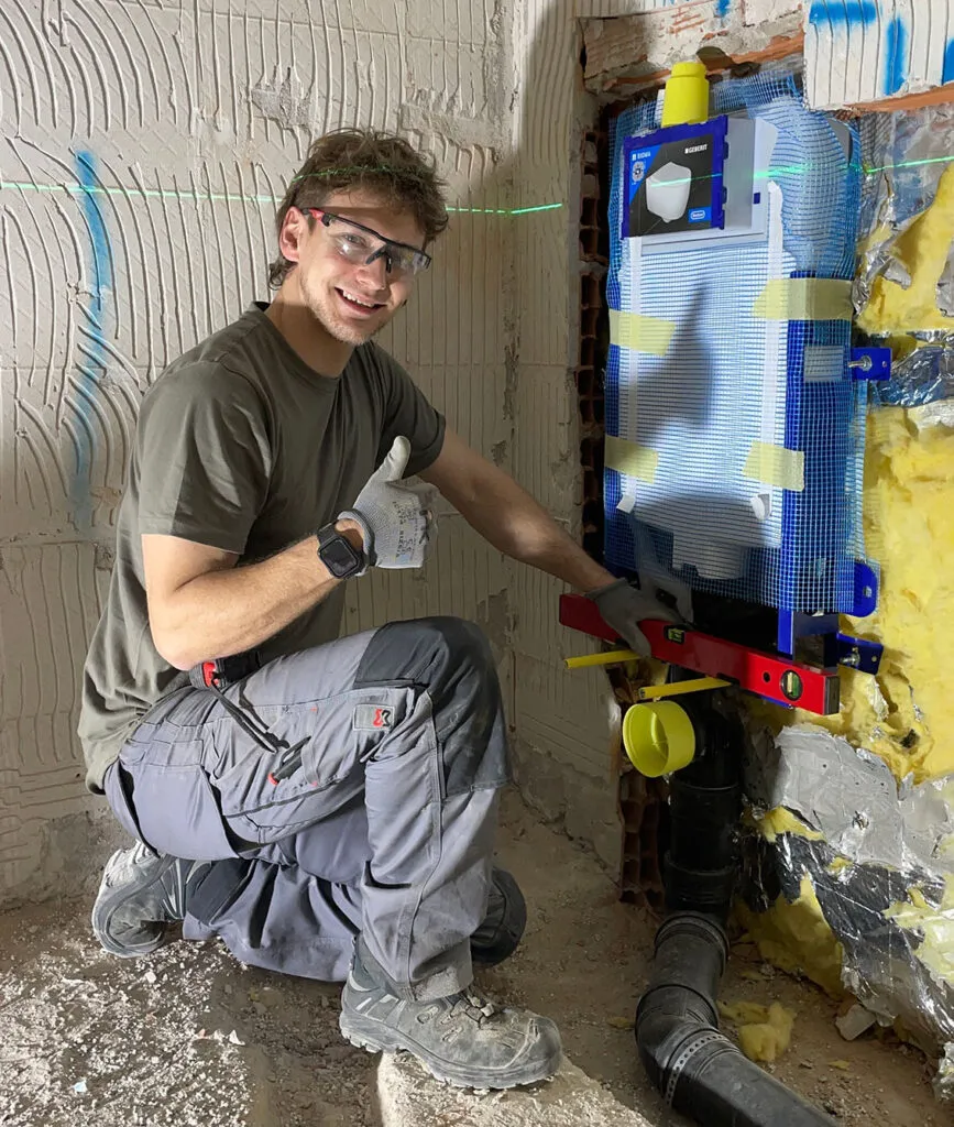 Alessio Aldrighetti in cantiere, in ginocchio davanti a una cassetta a incasso appena montata