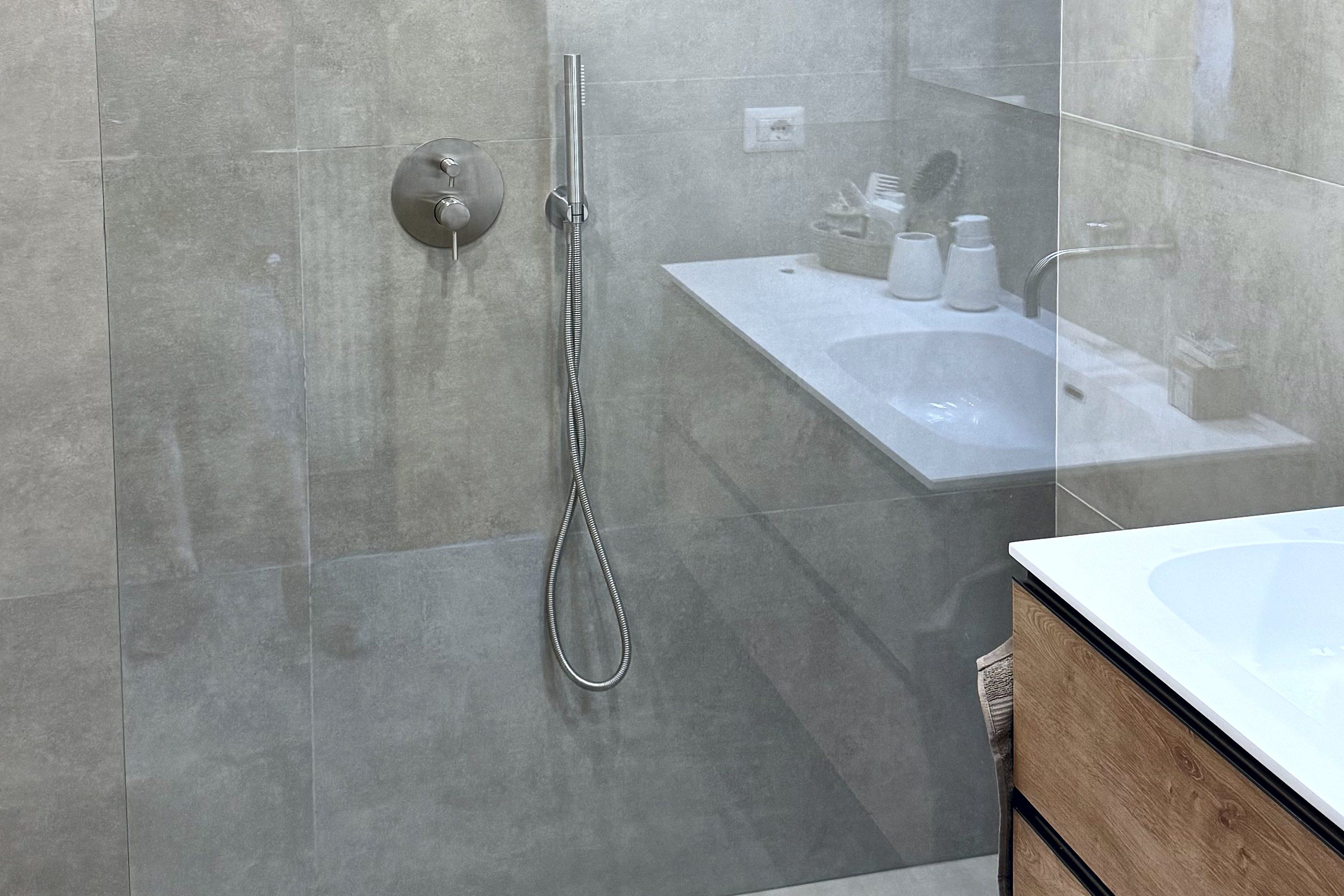 Bagno rifatto: doccia a filo pavimento con parete in vetro, miscelatore a incasso e piastrelle grigie
